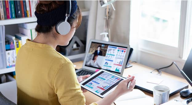 タブレットで企業分析を行うヘッドフォン姿の女性