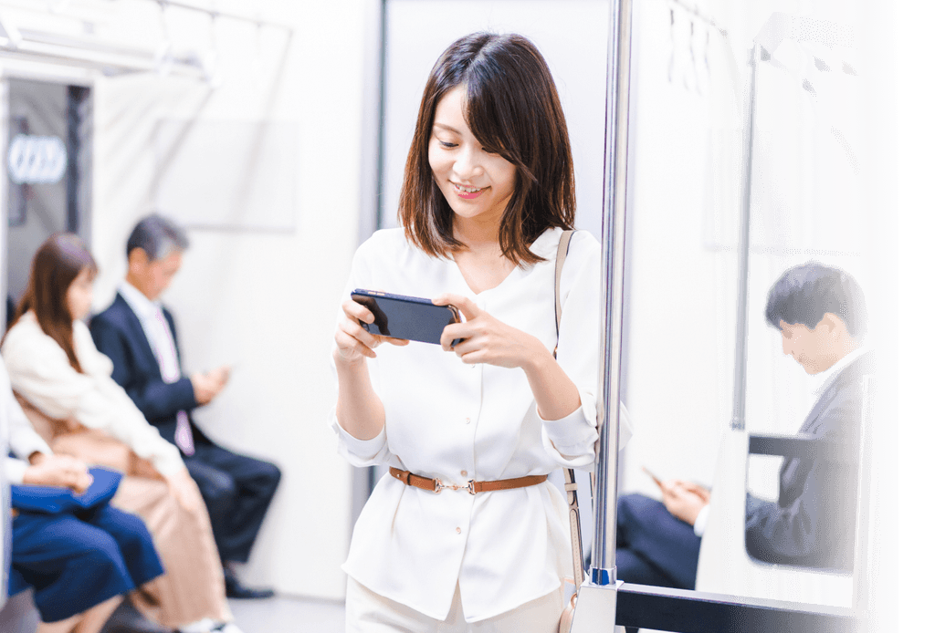 電車内でスマートフォンを操作する若い女性